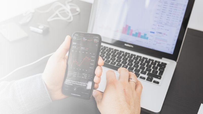 Profesional utilizando herramientas de automatización con IA en smartphone y laptop para duplicar la productividad del equipo y monitorear métricas en tiempo real.